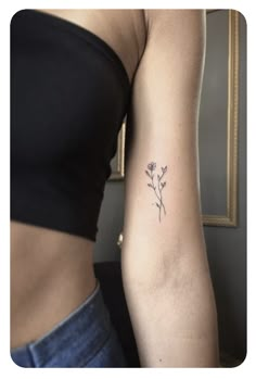 a woman's arm with a small flower tattoo on the left side of her arm