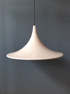 a white light hanging from a ceiling in a room with grey walls and flooring