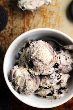 two scoops of ice cream in a bowl with oreo cookies on the side