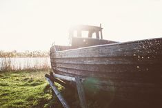 an old wooden boat sitting in the grass