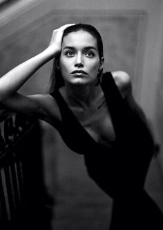 a black and white photo of a woman leaning against a railing with her hand on her head