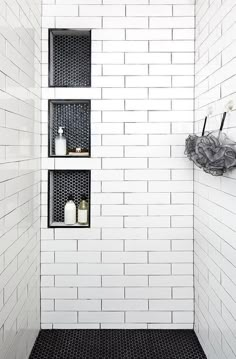 a black and white tiled bathroom with shelves on the wall