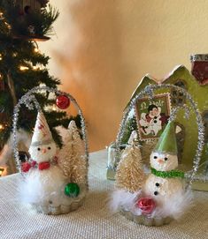 three snowmen sitting on top of a table next to a christmas tree and other decorations