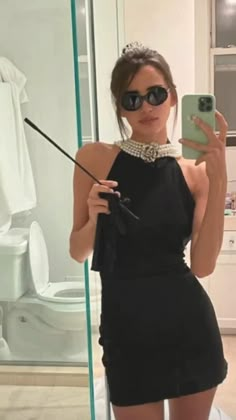 a woman taking a selfie in front of a mirror with her cell phone and wearing sunglasses