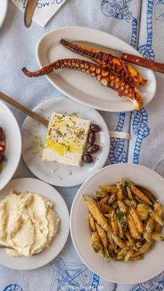 an assortment of food items on plates laid out on a blue and white table cloth