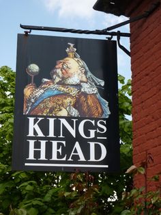 a sign hanging from the side of a building that says king's head on it