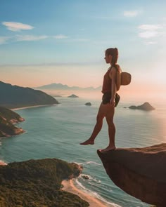 a woman standing on top of a cliff overlooking the ocean