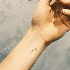 a person's arm with a small tattoo on the left side of their wrist