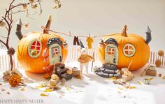 two pumpkins with small houses on them and some decorations around the house in front