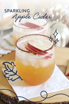 two glasses filled with apple cider sitting on top of a table