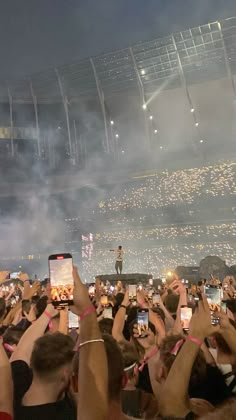 a crowd of people holding up their cell phones in front of an audience at a concert