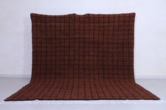 a brown and black checkered blanket sitting on top of a white floor next to a wall