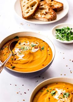 two bowls of soup with bread on the side