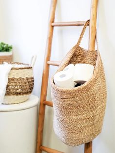 two rolls of toilet paper sitting in a basket next to a ladder