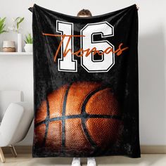 a woman holding up a black and white basketball blanket with the number 16 on it