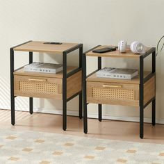 two side tables with drawers on each one and a plant next to them in front of a white wall