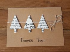 three small christmas trees are tied up on a piece of brown paper with words written in them