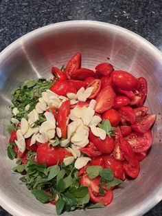 a metal bowl filled with lots of red and white food on top of a table