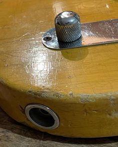 a close up of a wooden guitar with a metal object on it's top