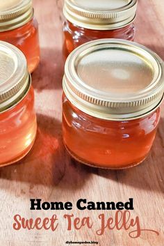 four jars filled with sweet tea jelly sitting on top of a wooden table