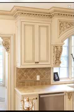 an ornate kitchen with white cabinets and gold accents