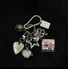 a keychain with some charms attached to it on a black surface next to a dice