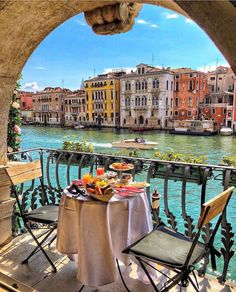 an outdoor table with food on it overlooking the water and buildings in venice, italy