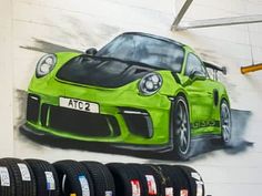 a green sports car painted on the side of a wall next to some black tires