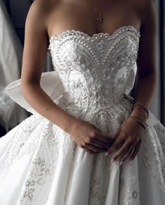 a woman in a wedding dress is holding her hands on her waist