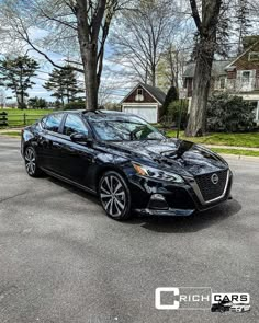 a black car parked in front of some trees