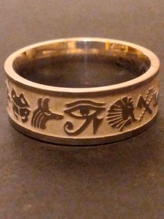 You are buying the Egyptian inspired ring pictured, it features a wonderful stainless  steel band with Egyptian symbols etched all the way around. This wonderful ancient Egyptian pattern inspired Ring will look amazing, very classic look, a great silver-tone accessory for that Egyptian look. Available in size 9  , these lovely rings are new old stock I got them from a costume jewelry warehouse that went out of business in the late 1990s. Please Note: These are comfort fit rings (rounded on the i Ancient Egyptian Jewelry Rings, Ancient Egyptian Accessories, Symbolic Silver Jewelry With Laser Engraving, Symbolic Silver Laser Engraved Jewelry, Symbolic Laser Engraved Silver Jewelry, Symbolic Nickel-free Engraved Ring, Symbolic Etched Bronze Jewelry, Symbolic Stainless Steel Engraved Ring As Gift, Symbolic Stainless Steel Engraved Ring For Anniversary