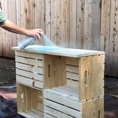 a person sprays disinfection on a table made out of pallets