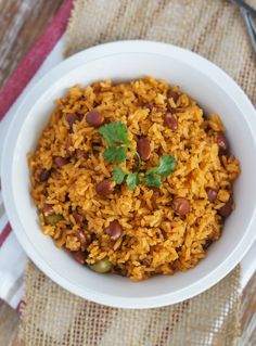 a white bowl filled with rice and beans on top of a table next to a fork