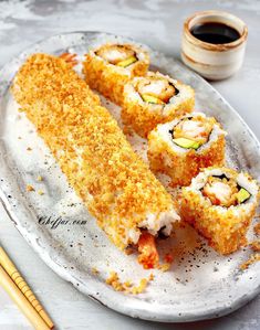 sushi on a plate with chopsticks next to it and a cup of coffee