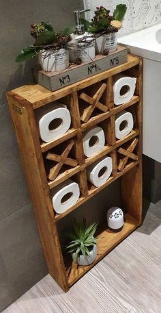 a wooden shelf filled with toilet paper rolls and potted plants next to a sink