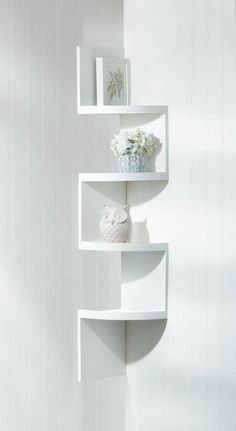 three white shelves with vases and pictures on them in the corner of a room