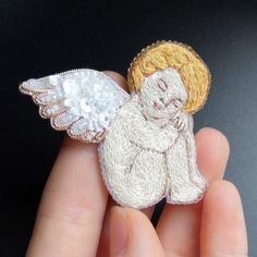 someone is holding a small brooch with an angel on it