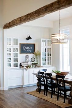 a dining room table with chairs and a chalkboard on the wall