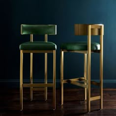 two green barstools in front of a dark blue wall and wooden flooring