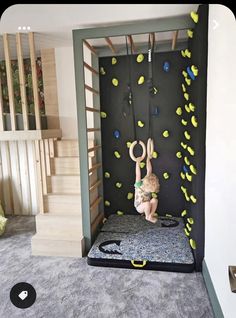 a child is climbing on a climbing wall in a playroom with stairs and climbing ropes