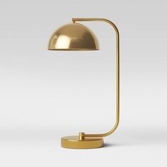 a gold lamp on a white background with the light turned on and one arm extended