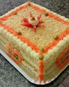 a square cake with orange and white frosting on a counter top, decorated with sprinkles