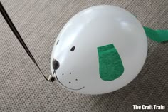 a balloon with a dog's head painted on it and a green ribbon hanging from the side