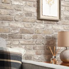 a living room with a couch and lamp next to a brick wall in the background