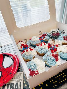 some cupcakes are in a box with spider - man decorations on them,