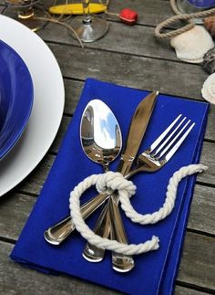 there is a blue napkin with silverware on it and a white rope around the edge