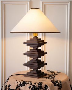 a lamp sitting on top of a table next to a white light shade over it