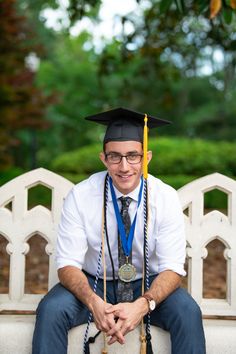 a man wearing a graduation cap and gown sitting on a bench