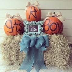 three pumpkins sitting on top of hay bales in front of a house