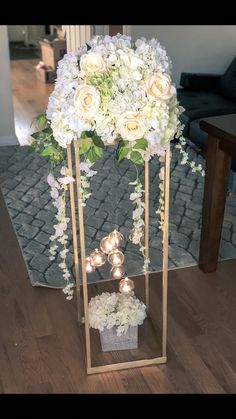 a vase filled with white flowers sitting on top of a wooden floor next to a table